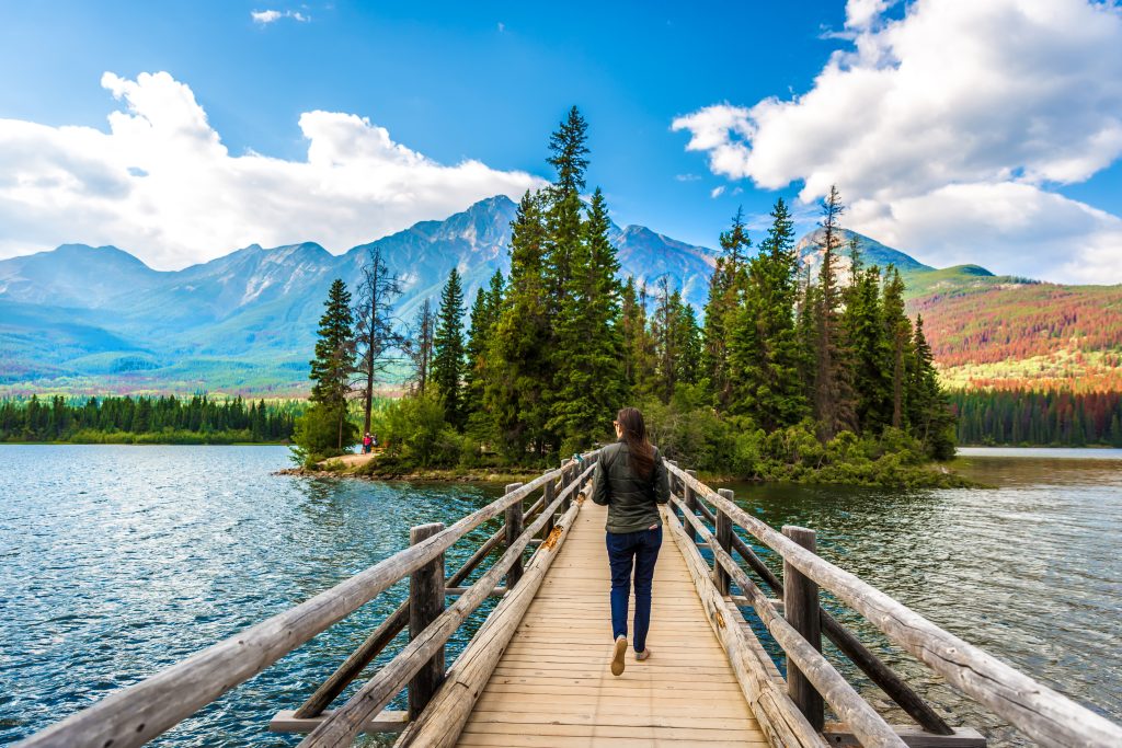 Young woman walking on a wood bridge over a lake in Jasper National Park, Canada.